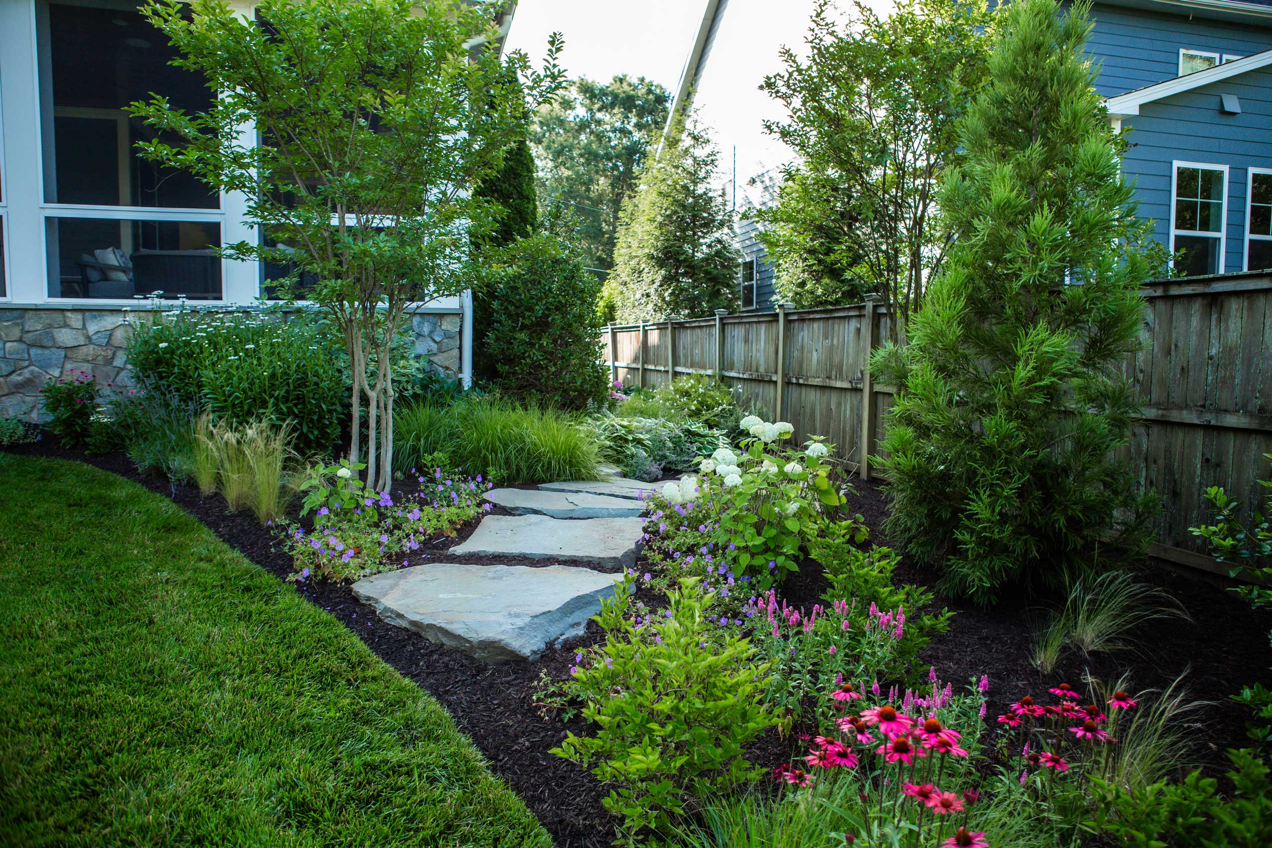 a garden with a stone path and flowers